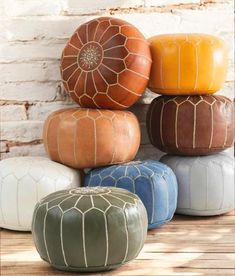 several different colored poufles stacked on top of each other in front of a brick wall