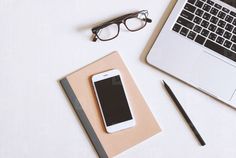 an open laptop computer sitting on top of a desk next to a notebook and eyeglasses