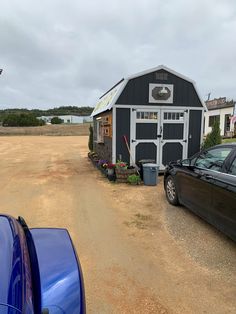 two cars parked in front of a barn