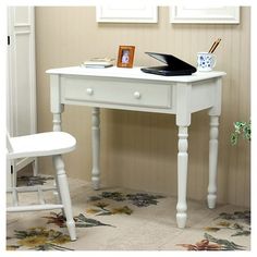 a white desk with a laptop on it and pictures hanging above the desk in front of it