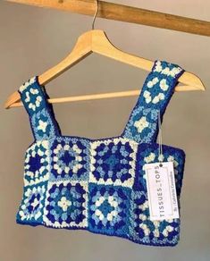 a blue and white crocheted bag hanging from a wooden hanger