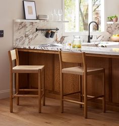 a kitchen with marble counter tops and wooden chairs