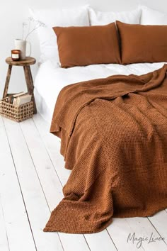 a bed with brown blankets and pillows on top of it next to a night stand