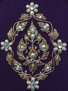 a gold brooch with flowers and leaves on purple velvet background, in the shape of a circle