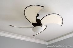 a ceiling fan with white and black blades hanging from it's center point in a room