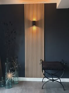 a chair and vases in front of a wall with vertical striped paneling on it