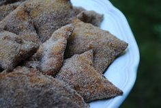 some sugared pastries are on a white plate with green grass in the background