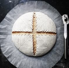 a piece of bread that has been made to look like a cross on it with a knife and fork next to it