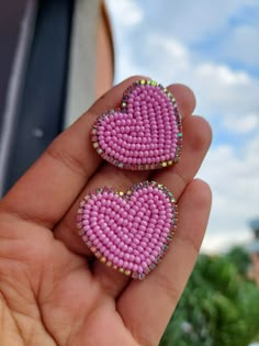 two pink heart shaped beads are held in someone's hand