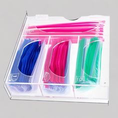 four different colored toothbrushes in a clear plastic box with dividers on each side