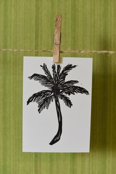 a piece of paper hanging on a clothes line with a palm tree drawn on it