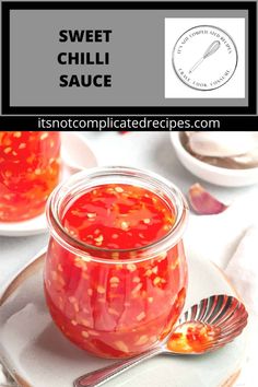 a jar filled with red sauce on top of a white plate next to a spoon