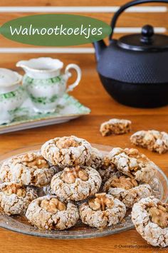 a plate full of cookies on a table next to a teapot and cup with saucer