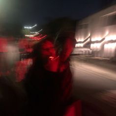 a blurry photo of two people walking down the street at night with lights in the background