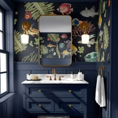 a bathroom with blue walls and wallpaper that has tropical designs on it, along with a gold framed mirror above the sink