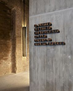 three metal letters are mounted to the side of a wall in an empty room with brick walls