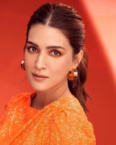 anusha ghatra in orange dress looking at the camera with big earrings on her head