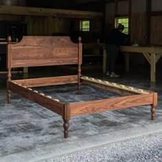 a wooden bed frame sitting on top of a cement floor