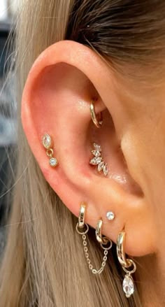 a woman wearing three different types of ear piercings