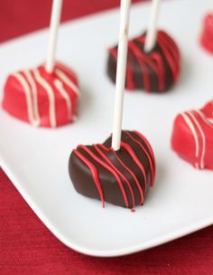 chocolate covered candies on a white plate with red and white striped candy sticks in the middle