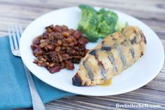 a white plate topped with meat, beans and broccoli next to a fork