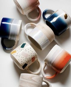 coffee cups are lined up on a white surface with different colors and shapes in them