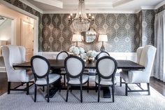 a dining room table with white chairs and chandelier in the middle of it