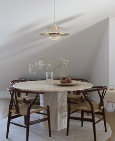 a round table with chairs around it in the middle of an empty room, surrounded by white walls and wood flooring