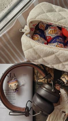 an open bag with candy and headphones in it next to a box filled with candies