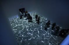 people are standing in the middle of a room with water on the floor and light shining through