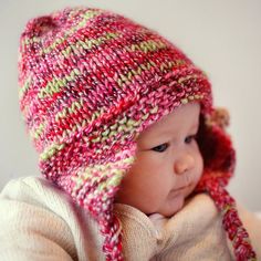 a close up of a baby wearing a knitted hat and holding it's head