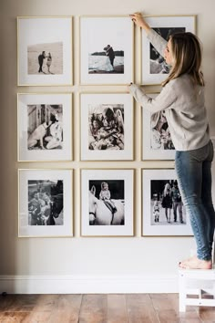 a woman hanging pictures on the wall