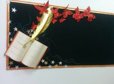 an open book with red paper flowers on it and a feather quill in the middle