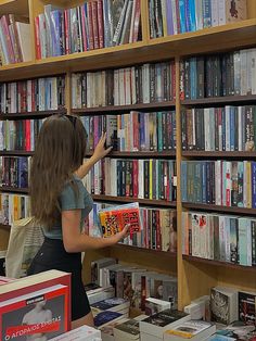 a woman standing in front of a bookshelf filled with lots of different types of books