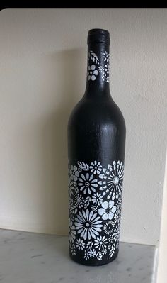 a black bottle with white flowers painted on it