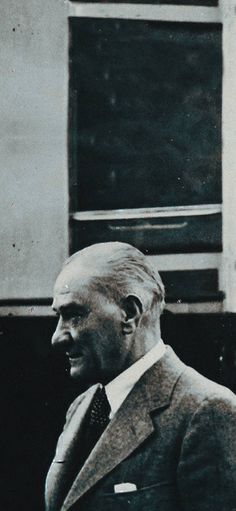 an old black and white photo of a man in a suit looking off into the distance