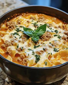 a pot filled with pasta and meat covered in parmesan cheese, basil leaves