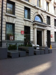 the front entrance to an office building with benches and planters on the sidewalk in front