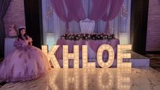 a woman in a purple dress standing next to a sign that says khloe