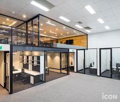 an empty office with glass walls and desks in the center, on top of carpeted flooring