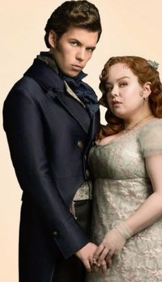 a man and woman dressed in period clothing posing for the camera, with one holding her hand on his hip