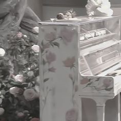 a white piano sitting in front of a flowered bush with roses on it's sides