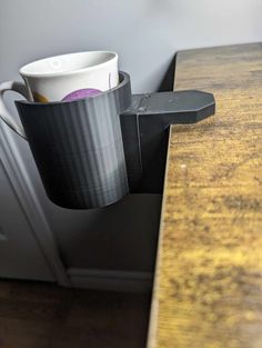 a coffee cup sitting on top of a wooden table next to a metal door handle