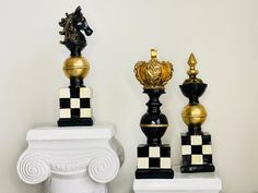 three black and gold chess pieces on white pedestals