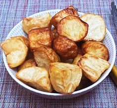 a white bowl filled with fried potatoes on top of a blue and purple table cloth