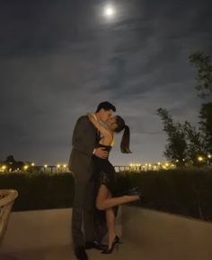 a man and woman are kissing under the moon