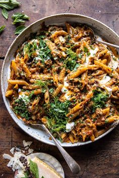 a bowl filled with pasta and sauce on top of a wooden table