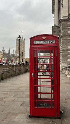 a red phone booth sitting on the side of a road