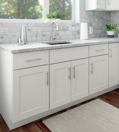 a kitchen with white cabinets and marble counter tops, along with a rug on the floor