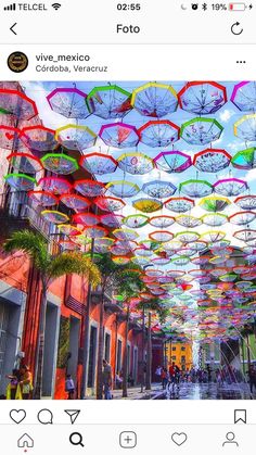 an instagram page with umbrellas hanging from the ceiling and people walking down the street